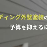 サイディング外壁塗装の予算を抑える方法を紹介する記事のアイキャッチ画像。グレーのサイディングが背景に使用されており、黄色と白色の文字でタイトルが表示されている。